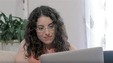 a female college student looking at the screen of her silver-cased laptop computer