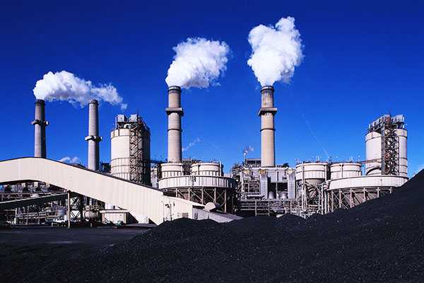 pile of coal in the foreground and coal-fired power plant in the background