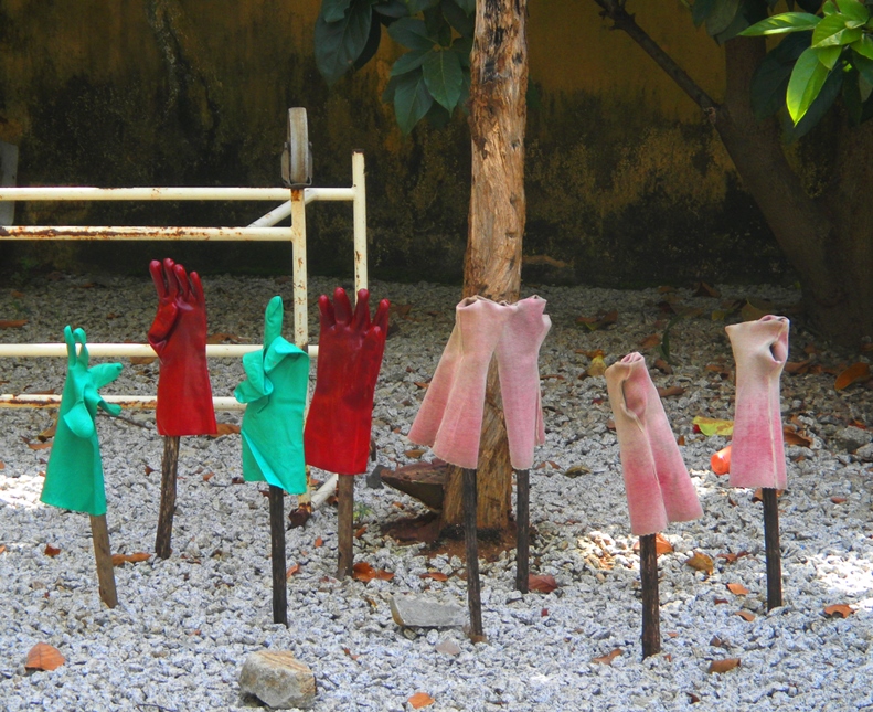 Red-, pink-, and green-colored rubber gloves propped up on sticks in order to dry