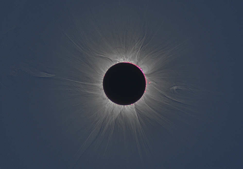 A black disk surrounded by some pink beads, with rays of light emanating in all directions against a dark blue sky