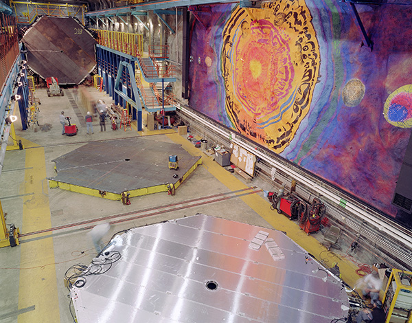 large room built underground with colorful mural on right wall and shiny polygonal equipment on the floor in the foreground