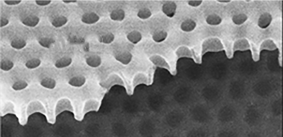 Scanning electron micrograph of a thin film of yttrium barium copper oxide, shown in grayscale with the material having regularly spaced holes