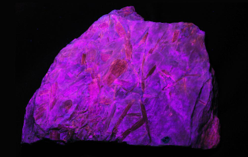 The mineral cummingtonite glows purple in ultraviolet light, demonstrating fluorescence, the absorption of higher-energy light and emission of lower-energy light