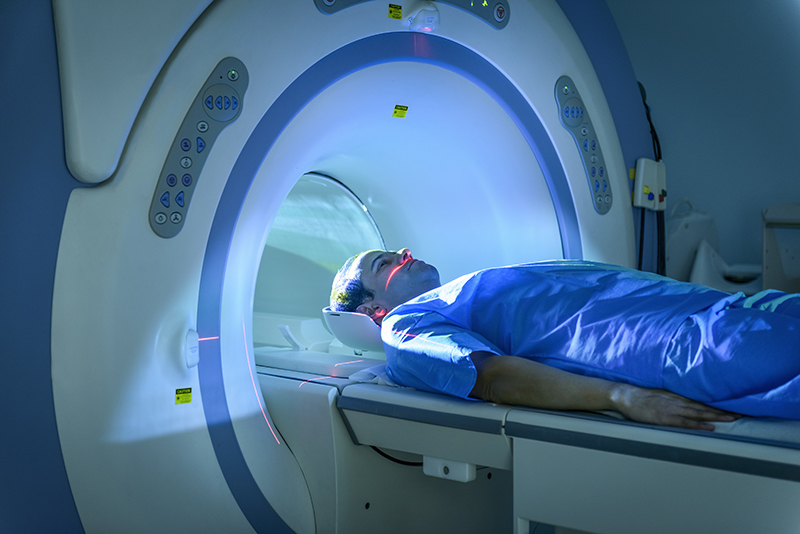 MRI scanner with patient lying on his back and with his head inside the machine