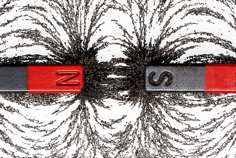 two bar magnets with opposite poles facing each other amidst iron filings