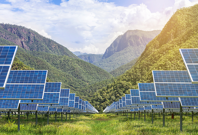 blue-colored solar panel array in front of green mountains