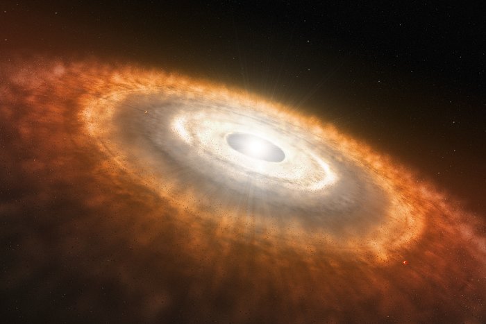 protoplanetary disk surrounds a young star, wherein planets are forming, shown as a bright white star-dot at center of a disk that is white towards its cneter and increasing more orange and brown towards the edges 